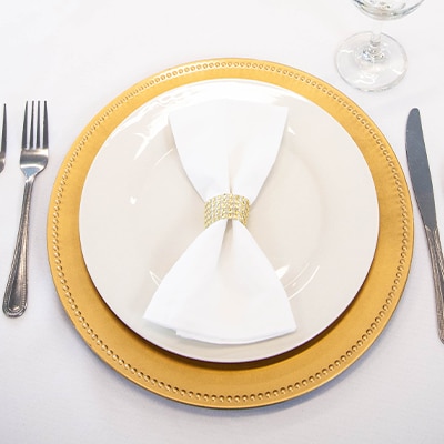 Wedding table placesetting with white dinnerware and a gold charger plate